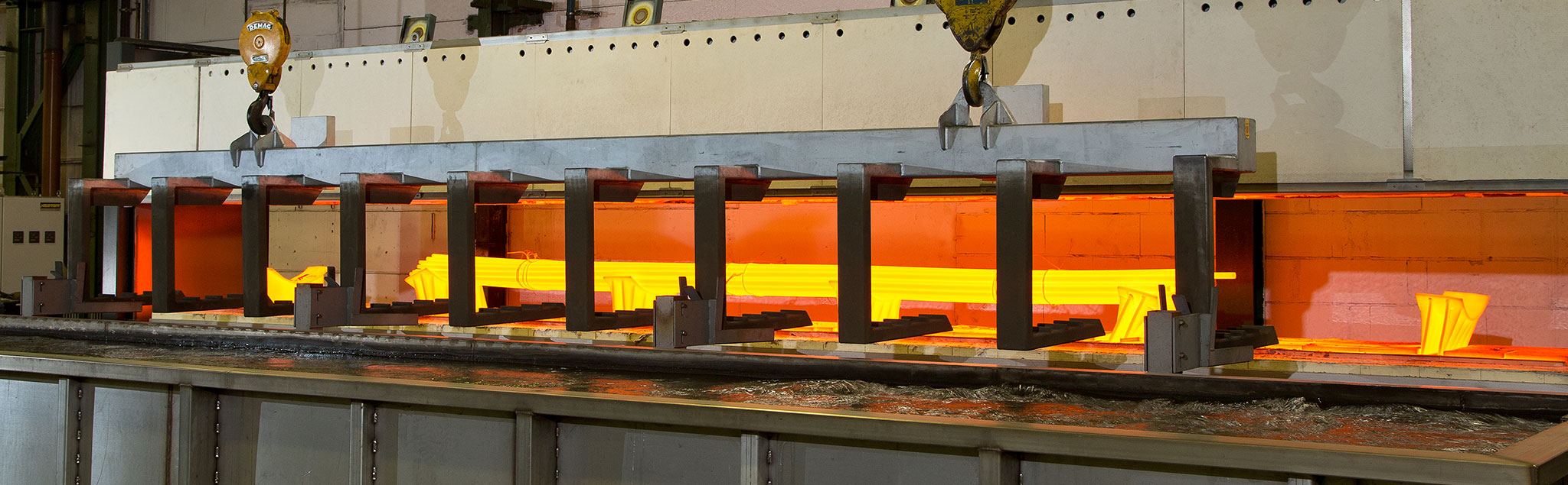 Hier sieht man einen geöffneten Herdwagenofen. Im inneren befinden sich glühende Stangen. Im Vordergrund erkennt man das Wasserbecken.